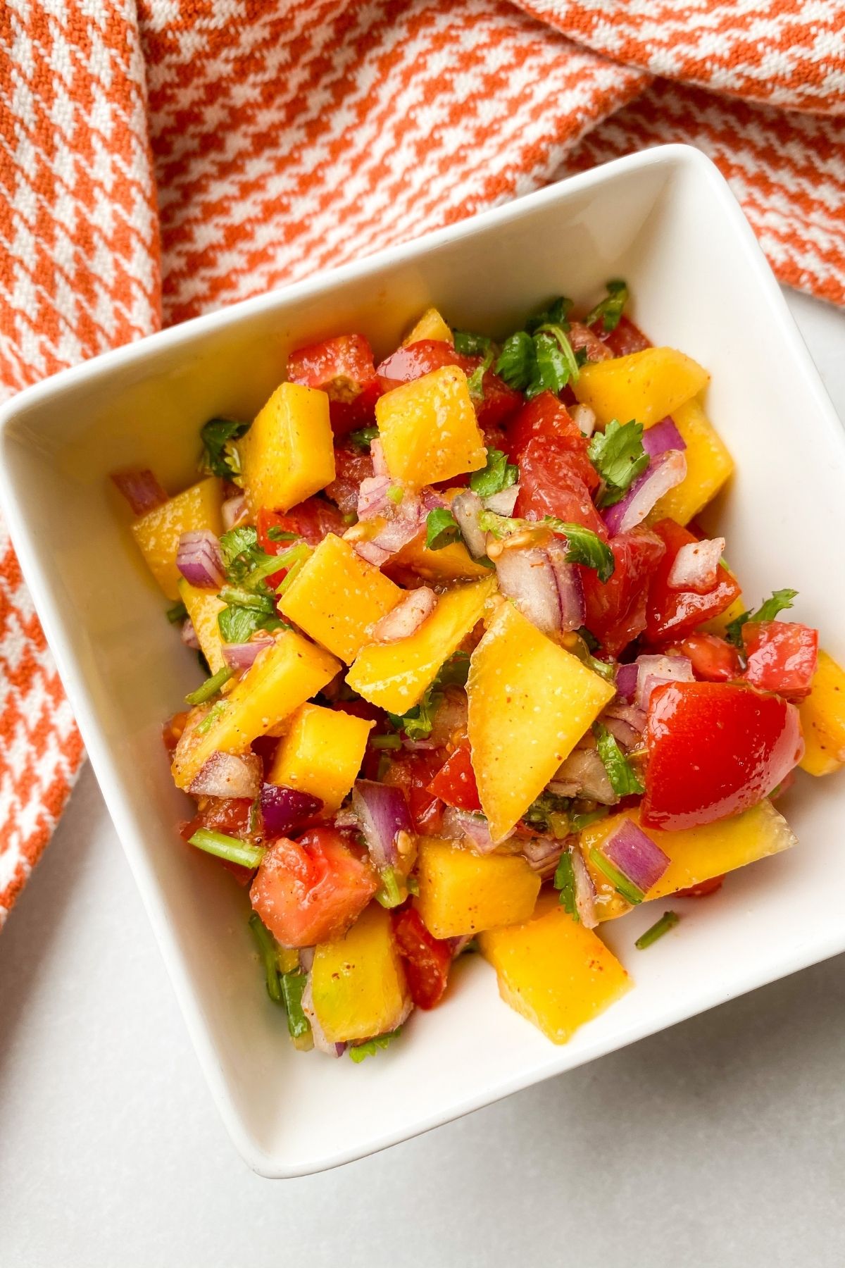 mango pico de gallo in white bowl with dish towel