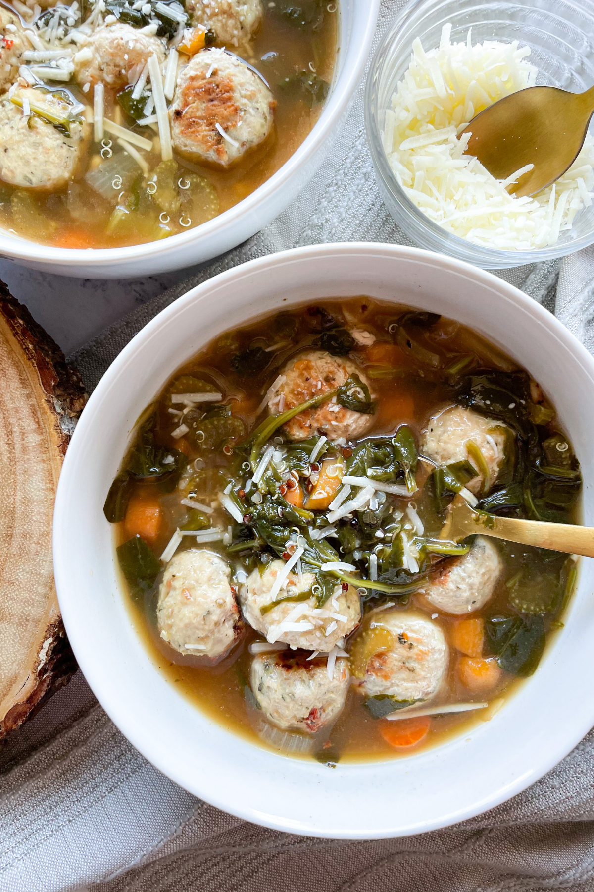 Healthy Italian Wedding Soup in 2 White Bowls, Gold Spoons and Cheese
