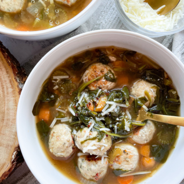 Healthy Italian Wedding Soup in 2 White Bowls, Gold Spoons and Cheese