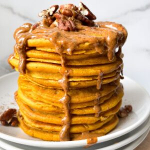 stacked pumpkin pancakes with almond butter and pecans