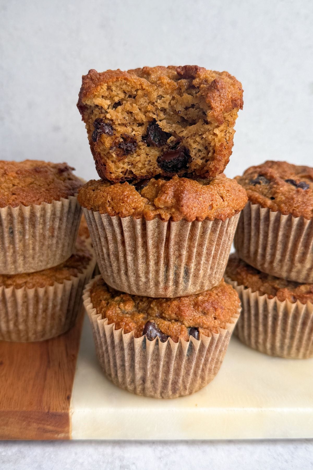 Almond flour banana muffins stacked on a board.