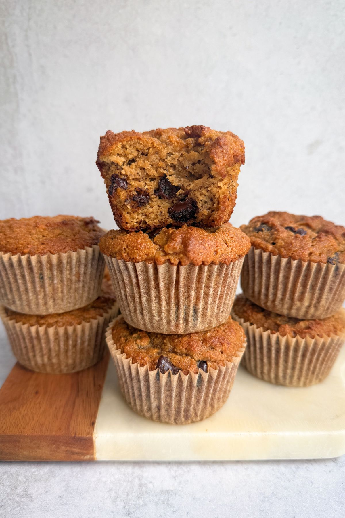 Almond flour banana muffins stacked on a board.